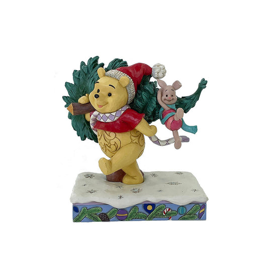 "Disney Traditions figurine van Winnie the Pooh en Piglet die samen een kerstboom dragen, ontworpen door Jim Shore in folk-art stijl."