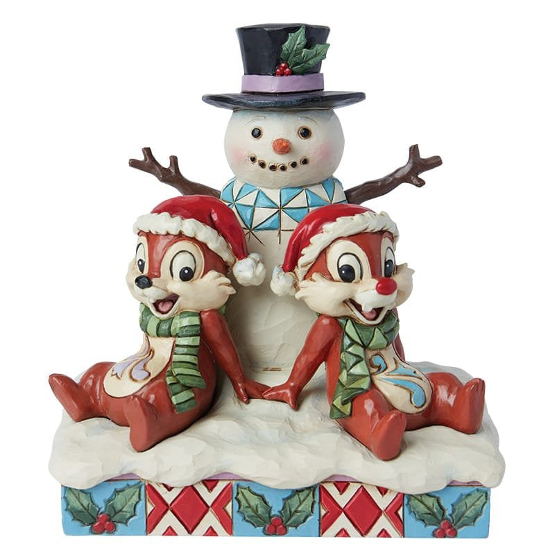 Knabbel en Babbel uit de Disney Traditions-collectie staan vrolijk naast een sneeuwpop, handbeschilderd beeldje in warme kerstkleuren met sierlijke details in houtsnijstijl.
