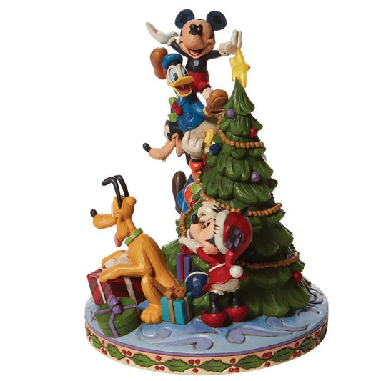 Handgeschilderd Disney beeldje van Merry Tree Trimming toont Mickey en Pluto met een kerstboom, afgewerkt in traditionele quilt- en houtsnijpatronen.