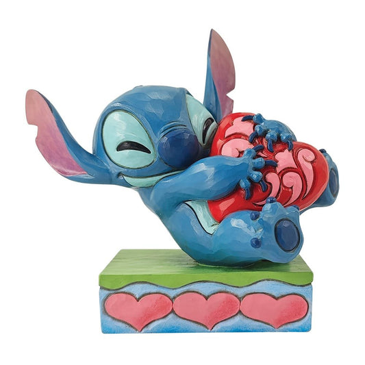 Handgemaakt Stitch Hugging Heart-beeldje uit de Disney Traditions-collectie van Jim Shore, met levendige kleuren en een hartje dicht tegen zijn borst.