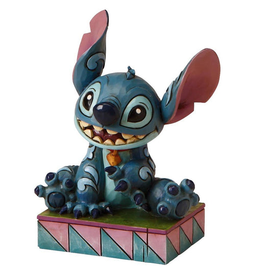Jim Shore Personality Poses beeldje van Stitch met zijn kenmerkende ondeugende glimlach, handgemaakt en handbeschilderd uit gegoten steen, geleverd in een stijlvolle geschenkdoos.