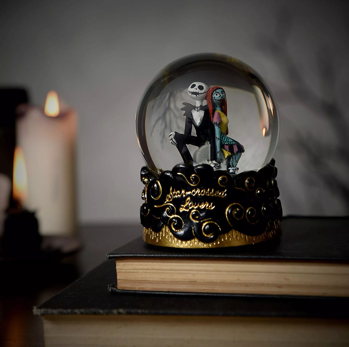 Betoverende sneeuwbol met Jack Skellington en Sally uit The Nightmare Before Christmas, met dwarrelende sneeuw en een sierlijke zwart-gouden voet met gotische patronen.