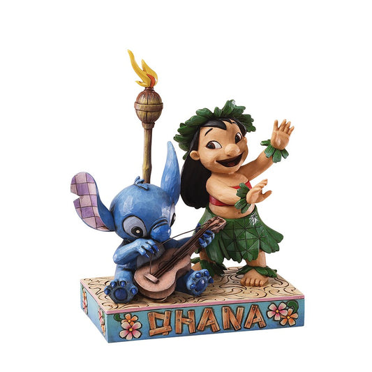 Enesco Jim Shore-beeldje van Lilo & Stitch, met Stitch op zijn Hawaiiaanse gitaar en Lilo die haar traditionele luau danst, versierd met kleurrijke patronen en rosemaling-details.