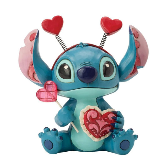 Enesco Jim Shore-beeldje van Stitch met haarband met hartje, een hartvormige lolly en een gequilt hart, versierd met rosemaling-details op zijn oren.